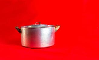 een oud aluminium pan gemaakt in ongeveer 1960 tegen een rood achtergrond. foto