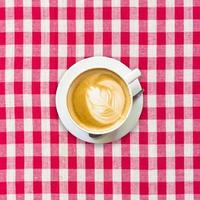 cappuccino koffie Aan wit en rood geruit achtergrond dichtbij omhoog foto