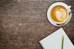 bovenstaand koffie en notitieboekje met potlood Aan hout structuur foto