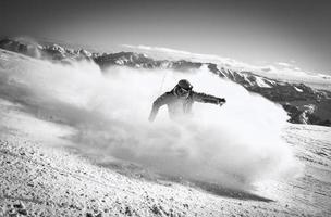 professioneel skiër Bij vol snelheid ski bergafwaarts Aan vers sneeuw Doen snijwerk in ski toevlucht terwijl opleiding voor wedstrijd in ski toevlucht met bergen achtergrond foto