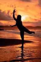 een Aziatisch tiener dansen ballet in zwart voor een festival door de strand foto