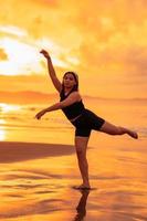 een Aziatisch tiener dansen ballet in zwart voor een festival door de strand foto