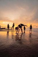 een groep van Indonesisch Dames aan het doen gymnastiek- opdrachten heel behendig Aan de strand foto