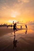 een groep van Aziatisch Dames in zwart kleren spelen met hun vrienden Aan de strand foto