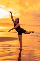 een Aziatisch tiener dansen ballet in zwart voor een festival door de strand foto