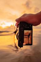 een camera met handen foto's een balinees vrouw aan het doen een gymnastiek- beweging Aan een zwart overhemd in de buurt de strand foto