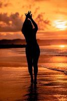 de silhouet van een Aziatisch tiener met een hoog lichaam is dansen ballet Aan de golven Aan de strand foto