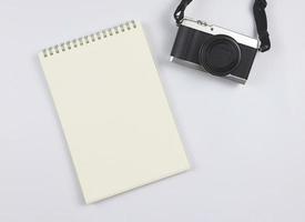vlak leggen van blanco bladzijde geopend notitieboekje en camera Aan wit achtergrond met kopiëren ruimte. foto en geheugen concept.