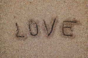 liefde geschreven op het zand op het strand foto