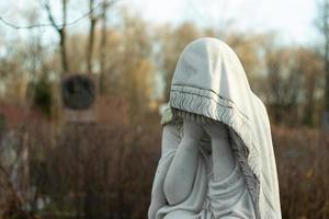 marmeren beeldhouwwerk van een rouwen vrouw in een begraafplaats. concept van verlies van een geliefde een en dood. kopiëren ruimte achtergrond foto