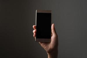 hand met smartphone geïsoleerd op zwarte achtergrond foto