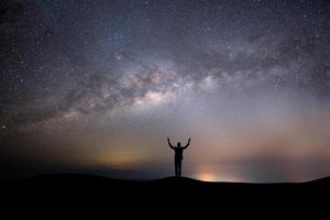 silhouet van een persoon bovenop een heuvel met sterren foto