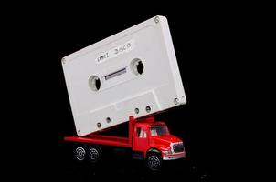 speelgoed- vrachtauto met een cassette plakband Aan zwart achtergrond foto