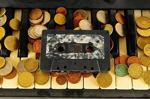 munten en een cassette plakband Aan piano sleutels foto