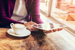 vrouw handen gebruik makend van en Holding computer tablet in koffie winkel met wijnoogst afgezwakt. foto