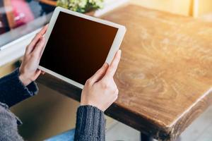 vrouw Speel tablet computer in koffie winkel met wijnoogst toon. foto