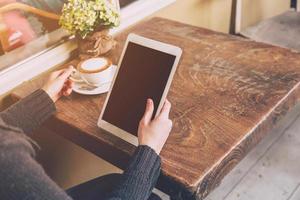 dichtbij omhoog hand- Aziatisch vrouw gebruik makend van tablet computer in koffie winkel met wijnoogst afgezwakt. foto