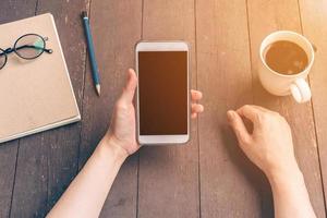 dichtbij omhoog hand- Azië vrouw gebruik makend van telefoon in koffie winkel met wijnoogst filter. foto