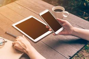 dichtbij omhoog hand- Azië vrouw gebruik makend van telefoon in koffie winkel met wijnoogst filter. foto