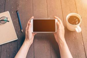 dichtbij omhoog hand- Aziatisch vrouw gebruik makend van telefoon in koffie winkel en zonlicht met wijnoogst filter. foto