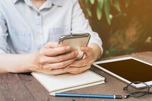 Aziatisch vrouw gebruik makend van telefoon in tuin Bij koffie winkel met wijnoogst toon. foto