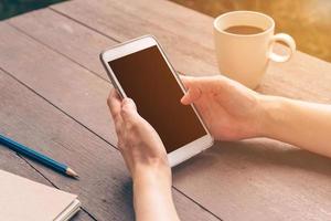 dichtbij omhoog hand- Aziatisch vrouw gebruik makend van telefoon in koffie winkel en zonlicht met wijnoogst filter. foto