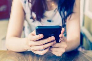 hand- vrouw gebruik makend van telefoon in koffie winkel met diepte van veld. foto