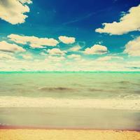 zand strand zee en blauw lucht wolken met wijnoogst toon. foto