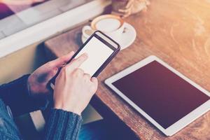 hand- vrouw gebruik makend van smartphone in koffie winkel en zacht licht met wijnoogst filter. foto