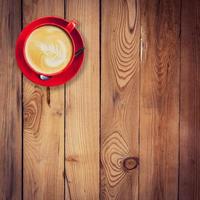 rood kop en latte koffie Aan hout tafel met ruimte. foto