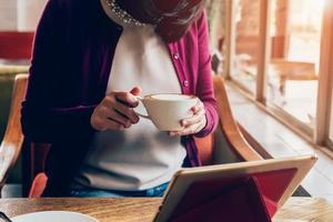 vrouw gebruik makend van tablet computer in koffie winkel met wijnoogst toon. foto