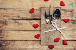 tafel reeks voor viering Valentijnsdag dag. houten tafel plaats instelling en zilverwerk met rood hart voor Valentijn dag. foto