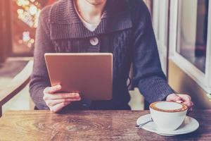 Aziatisch vrouw gebruik makend van tablet computer in koffie winkel met wijnoogst toon. foto