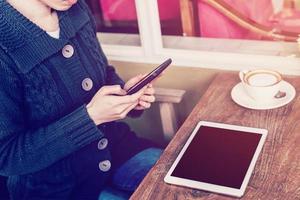 hand- vrouw gebruik makend van smartphone in koffie winkel en zacht licht met wijnoogst filter. foto