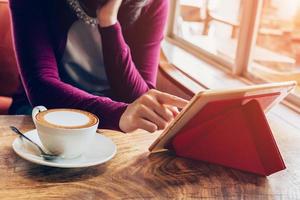 vrouw gebruik makend van tablet computer in koffie winkel met wijnoogst toon. foto