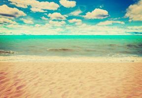 zand strand zee en blauw lucht wolken met wijnoogst toon. foto