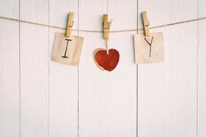 twee blanco oud papier en rood hart hangen. Aan wit houten achtergrond met wijnoogst stijl. foto