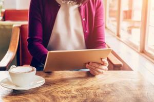 vrouw handen gebruik makend van en Holding computer tablet in koffie winkel met wijnoogst afgezwakt. foto