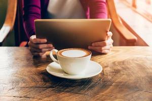 vrouw gebruik makend van tablet computer in koffie winkel met wijnoogst toon. foto