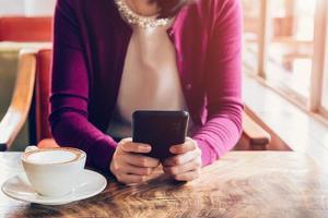 vrouw gebruik makend van mobiel telefoon in cafe. vrouw zittend in cafe en kop van koffie. foto