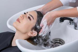 professioneel kapper het wassen haar- van jong vrouw in schoonheid salon. dichtbij omhoog van vrouw haar- in schoonheid salon, kapsel concept foto