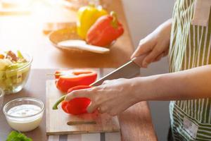 een jong vrouw bereidt zich voor klok paprika's voor haar ontbijt en is klaar voor een gezond maaltijd Aan de tafel met gezond, biologisch groenten Aan de tafel. gezond voedsel voorbereiding ideeën foto