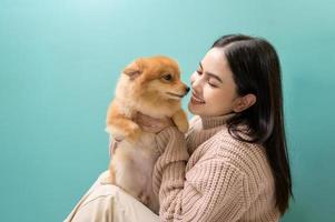 portret van jong mooi vrouw kusjes en knuffels haar hond over- groen achtergrond. foto