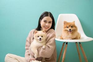 portret van jong mooi vrouw kusjes en knuffels haar hond over- groen achtergrond. foto