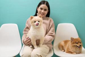 portret van jong mooi vrouw kusjes en knuffels haar hond over- groen achtergrond. foto