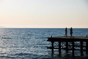 silhouetten van mensen Aan een verlaten pier foto