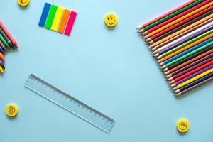 een reeks van helder schrijfbehoeften Aan een blauw achtergrond. gekleurde potloden, stickers en heerser foto