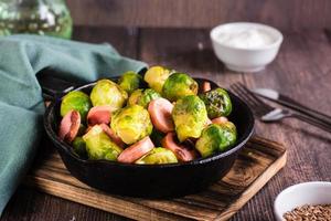 geroosterd Brussel spruiten met worstjes in een frituren pan Aan de tafel. huis diner. foto