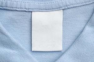 wit blanco wasserij zorg kleren etiket Aan blauw overhemd kleding stof achtergrond foto