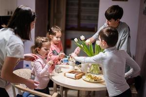 kinderen eten fruit en toetjes, drinken thee Bij huis in de avond keuken. foto